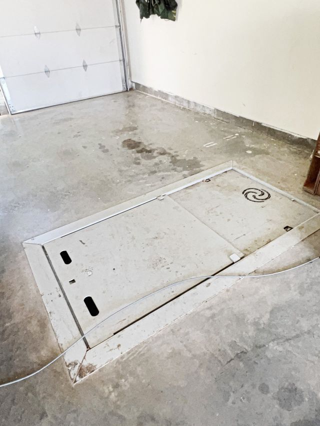 A manhole cover is sitting in a garage next to a garage door.