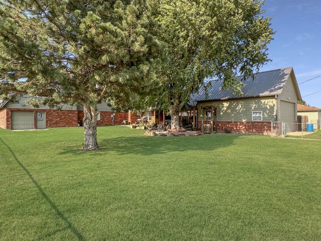 A house with a large lawn and trees in front of it.