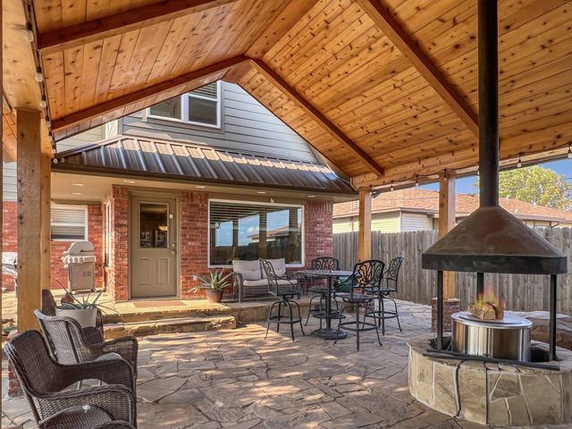 A patio with tables and chairs under a wooden roof