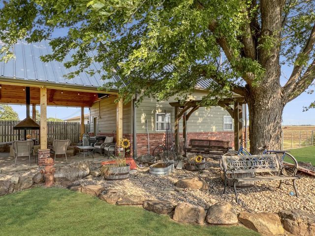 There is a large tree in the middle of the yard in front of a house.