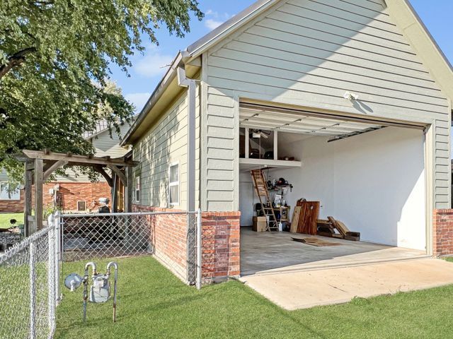 A garage with the door open and a chain link fence in front of it.