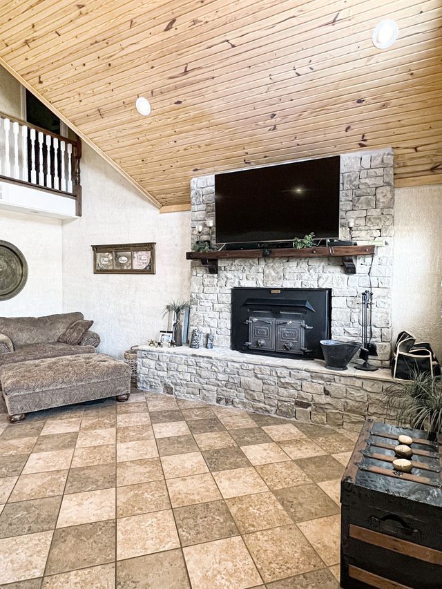A living room with a fireplace , couch , ottoman and television.