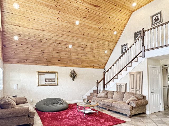 A living room with a wooden ceiling and stairs