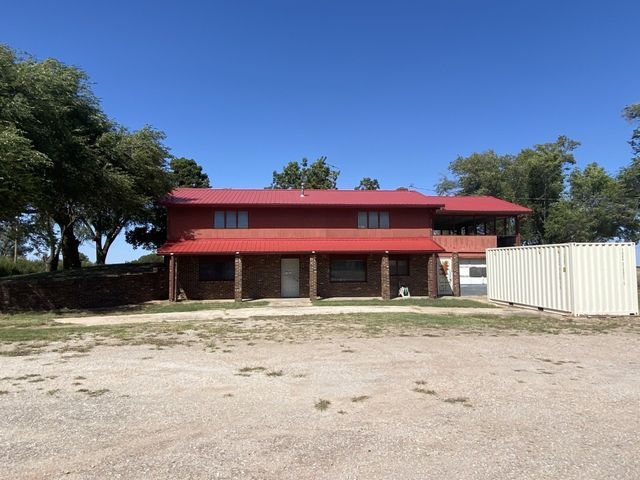 A large house with a red roof and a white fence in front of it