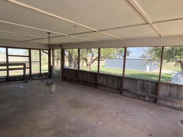 An empty room with a lot of windows and a ceiling fan.
