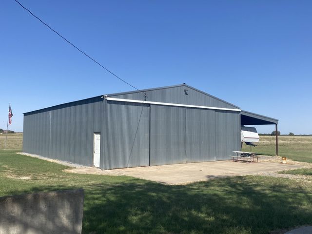 A plane hangar with a picnic table in front of it