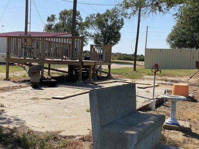 A concrete bench sits in front of a wooden deck