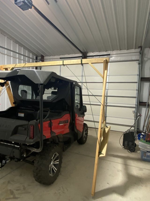 A red atv is parked in a garage next to a swing set.