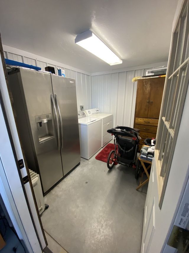 A laundry room with a refrigerator , washer and dryer , and a stroller.