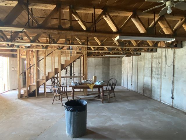 A basement with a table and chairs and a trash can