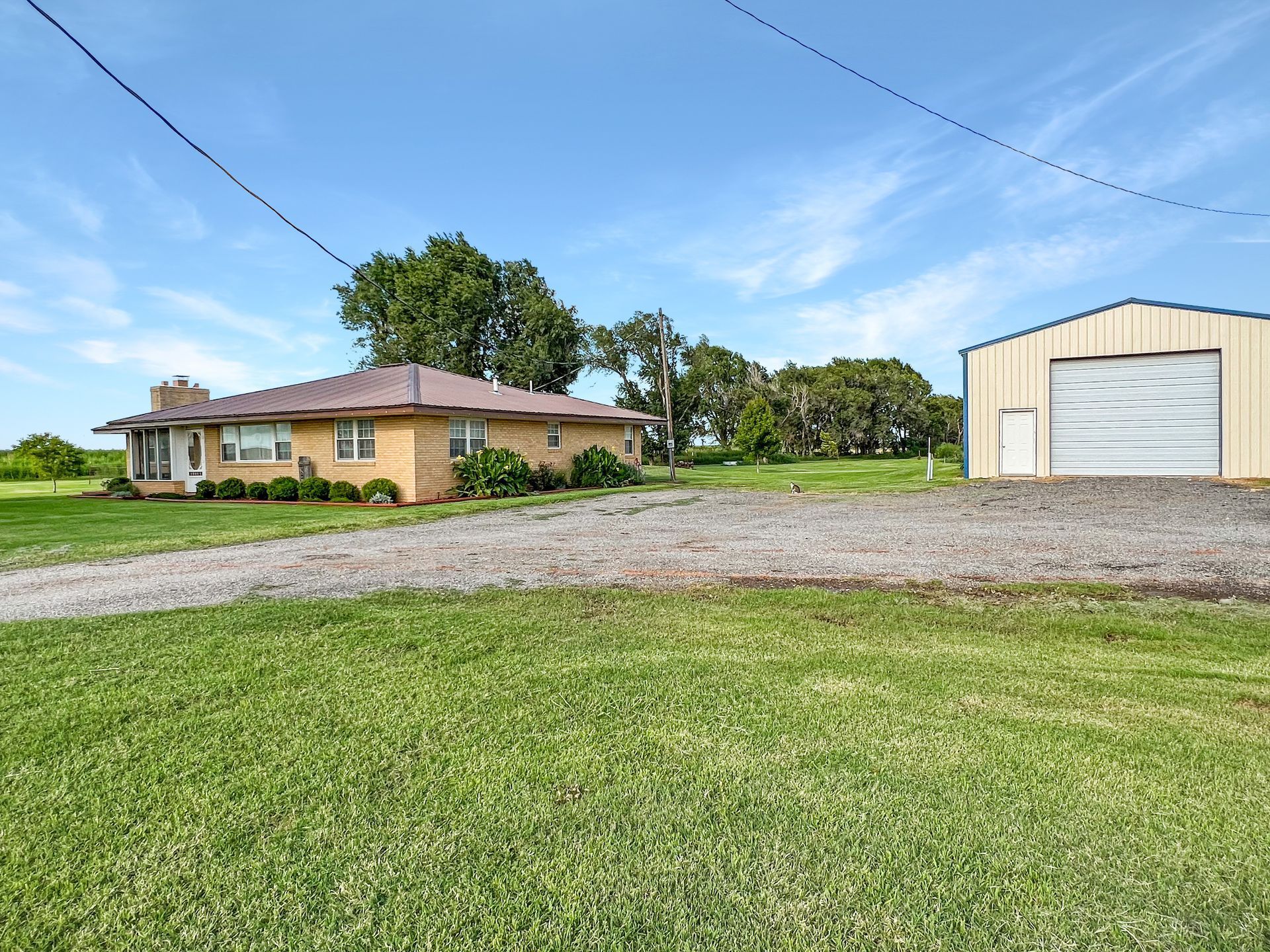 A house and a garage are sitting on top of a lush green field.