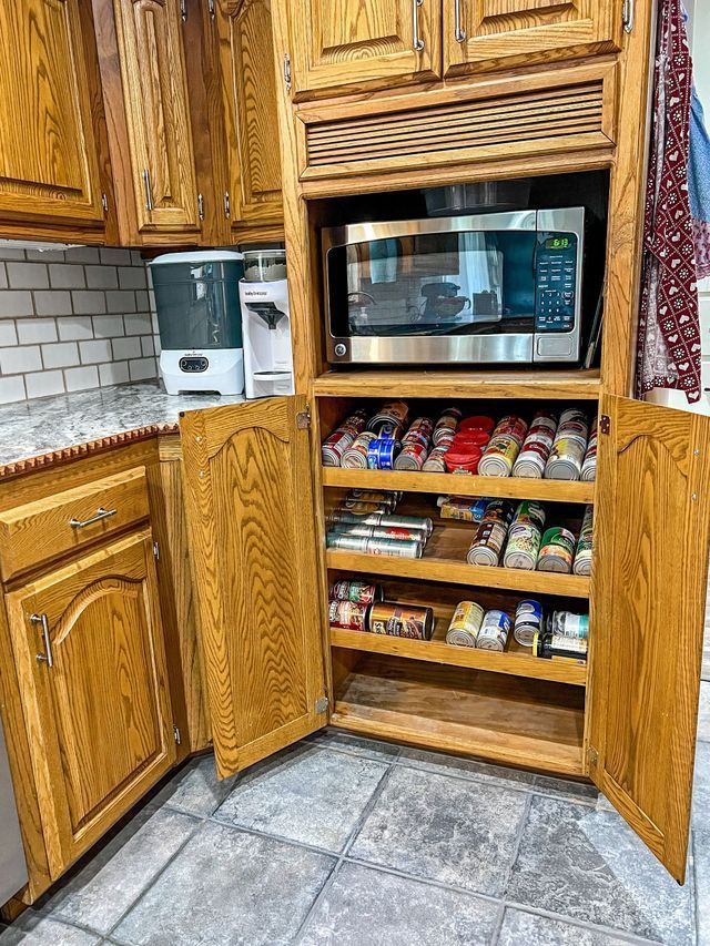 A kitchen with wooden cabinets , a microwave , and a pantry.