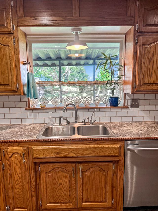 A kitchen with a sink , dishwasher , and window.