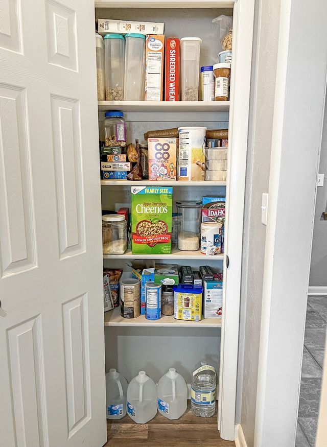 A pantry filled with cereal , milk , and water.