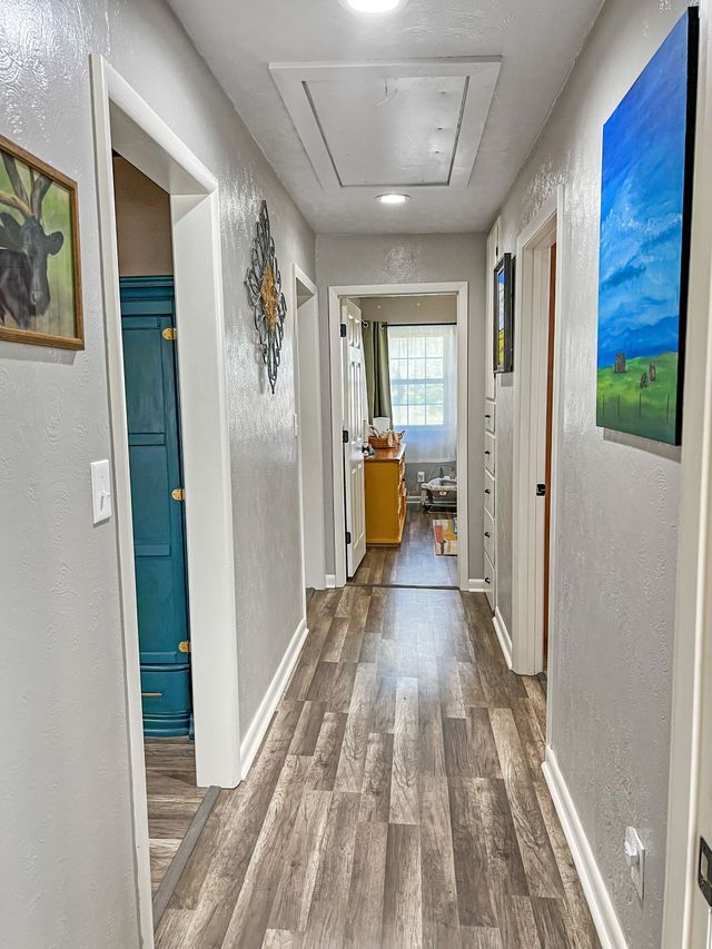 A long hallway with hardwood floors and a painting on the wall.