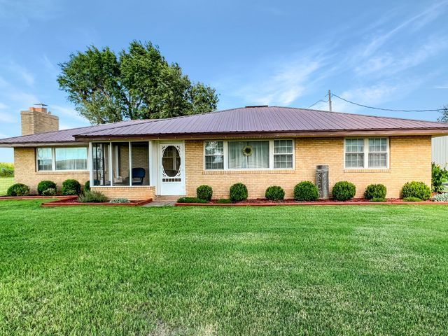 A large brick house with a lush green lawn in front of it.