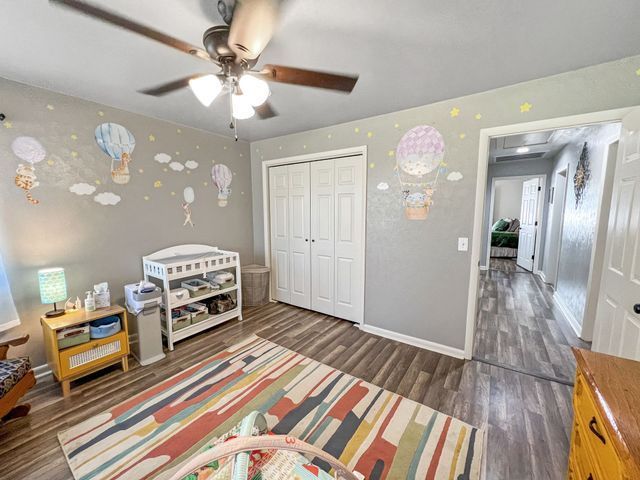 A bedroom with a ceiling fan and a changing table.