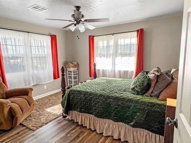 A bedroom with a bed , chair , and ceiling fan.