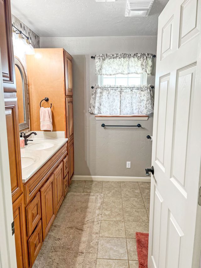 A bathroom with two sinks , a mirror , and a window.