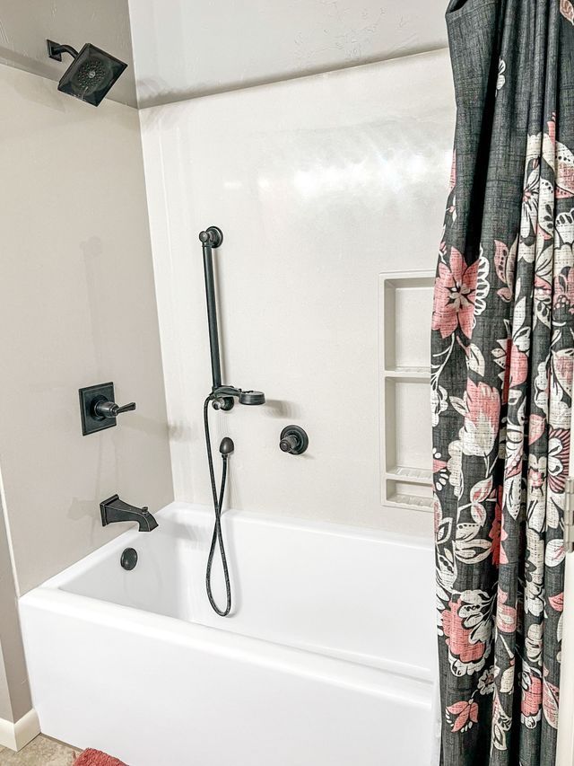 A bathroom with a bathtub , shower , and floral shower curtain.