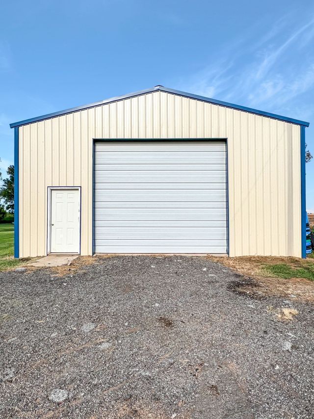 A metal building with a white garage door and a blue trim.
