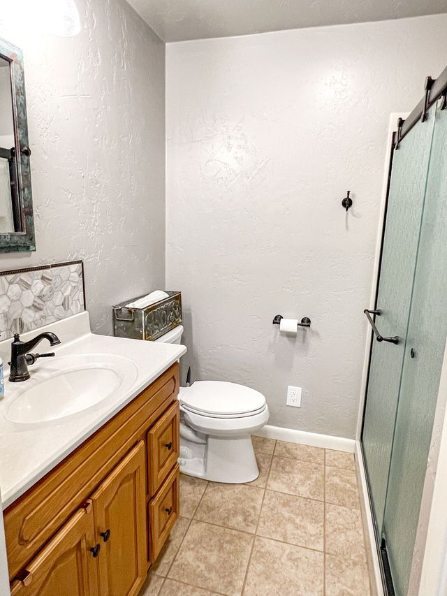 A bathroom with a toilet , sink , mirror and shower stall.