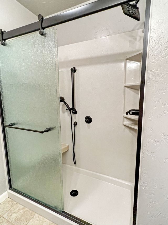 A bathroom with a sliding glass shower door and a shower head.