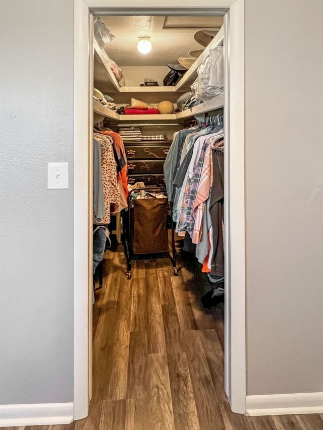 A walk in closet filled with clothes and a laundry basket.