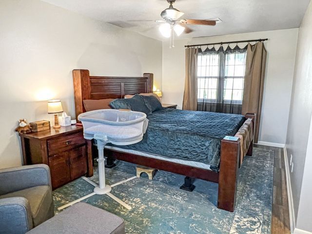 A bedroom with a bed , chair , nightstand and a crib.