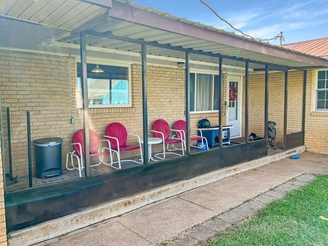 A brick house with a porch and chairs on it.