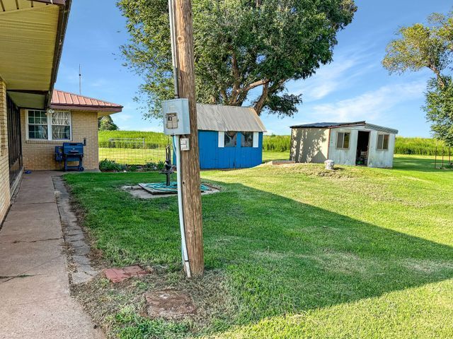 There is a blue shed in the middle of the grass next to a house.