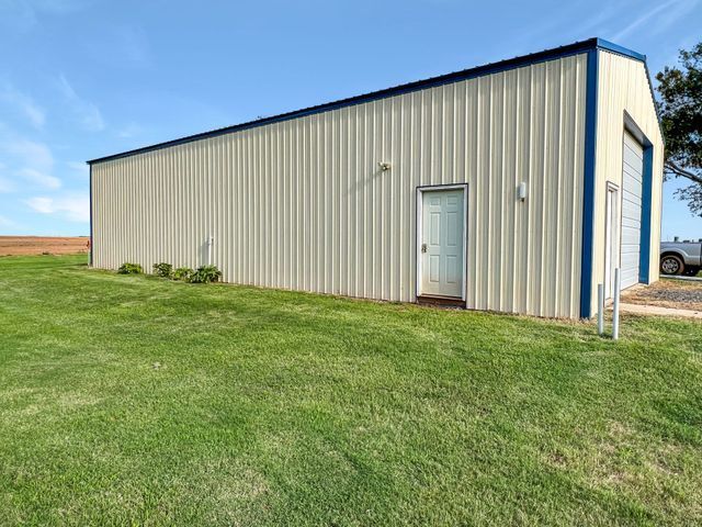 A large metal building is sitting in the middle of a lush green field.