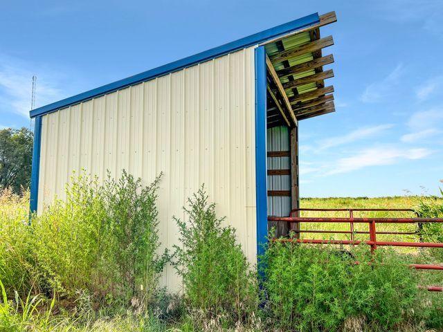 A white and blue barn is sitting in the middle of a field.