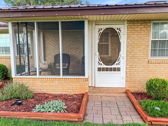 The front of a brick house with a screened in porch.