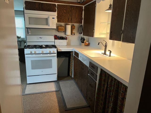 A kitchen with a stove , sink , and microwave