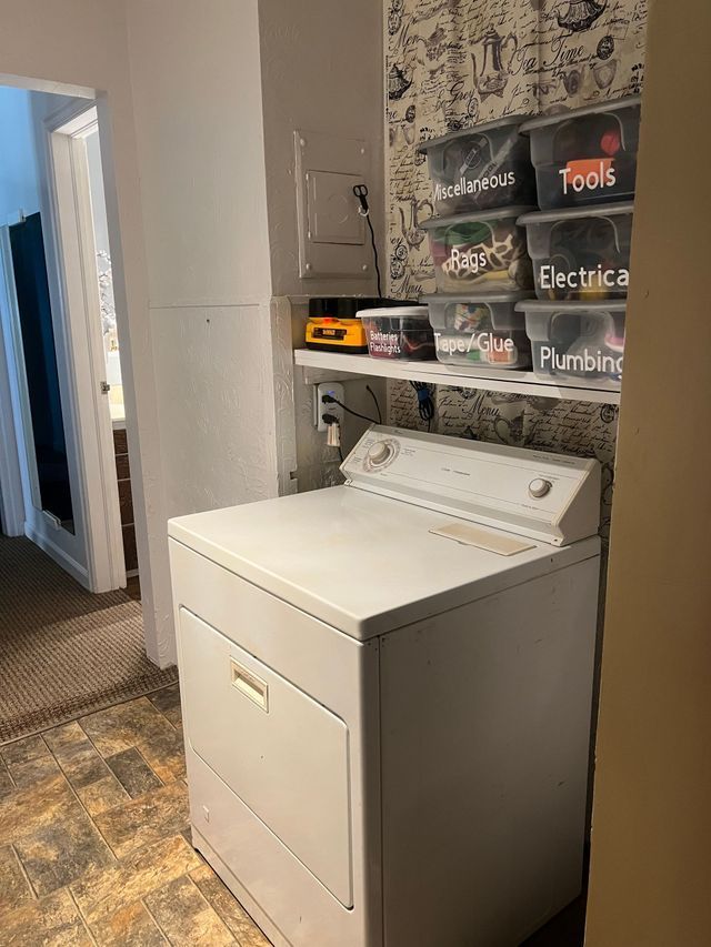 A white washer and dryer are sitting in a laundry room next to a shelf.