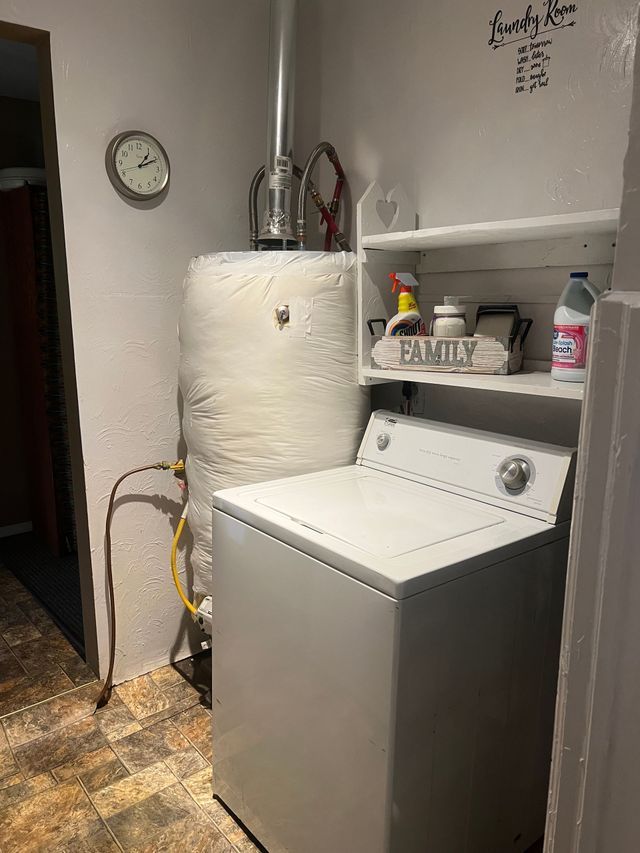 A washer and dryer are in a laundry room next to a water heater.