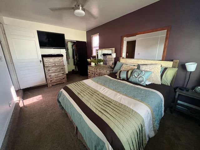 A bedroom with a large bed and a ceiling fan