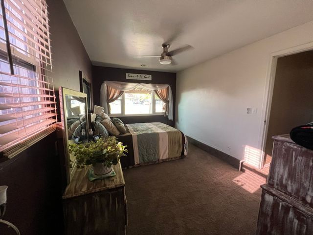 A bedroom with a bed , dresser , mirror and ceiling fan.
