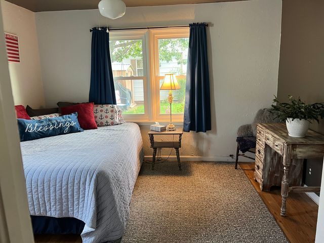A bedroom with a bed , desk , chair and window.