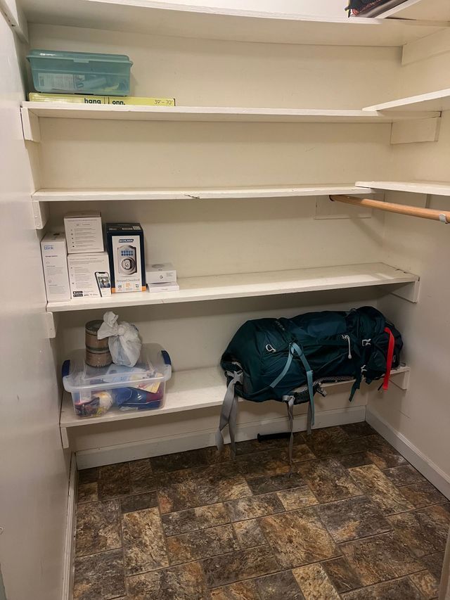 A closet with shelves and a backpack on the floor.