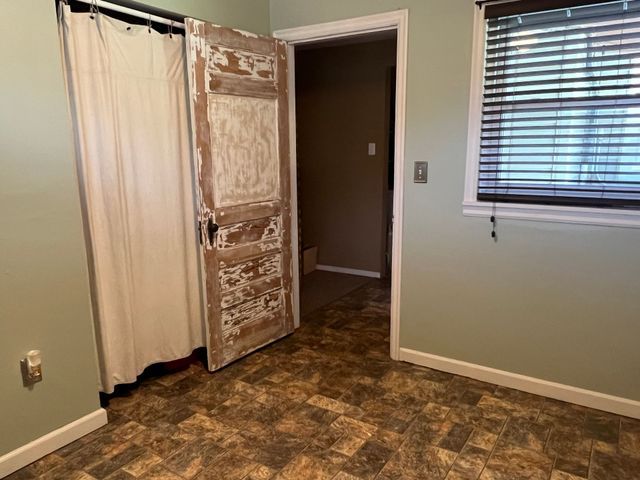 A room with a door and a window with blinds.