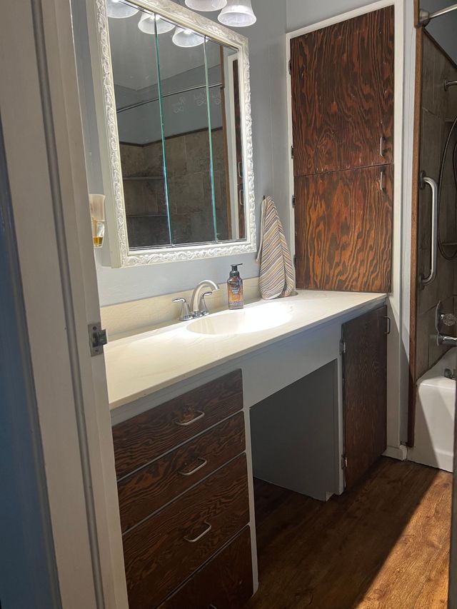 A bathroom with a sink , mirror and bathtub.
