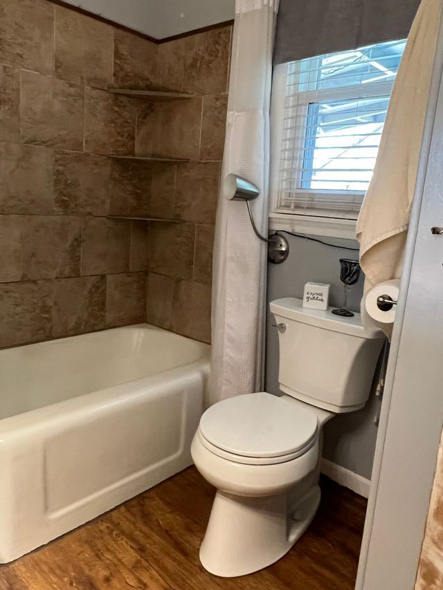 A bathroom with a toilet , tub and shower.