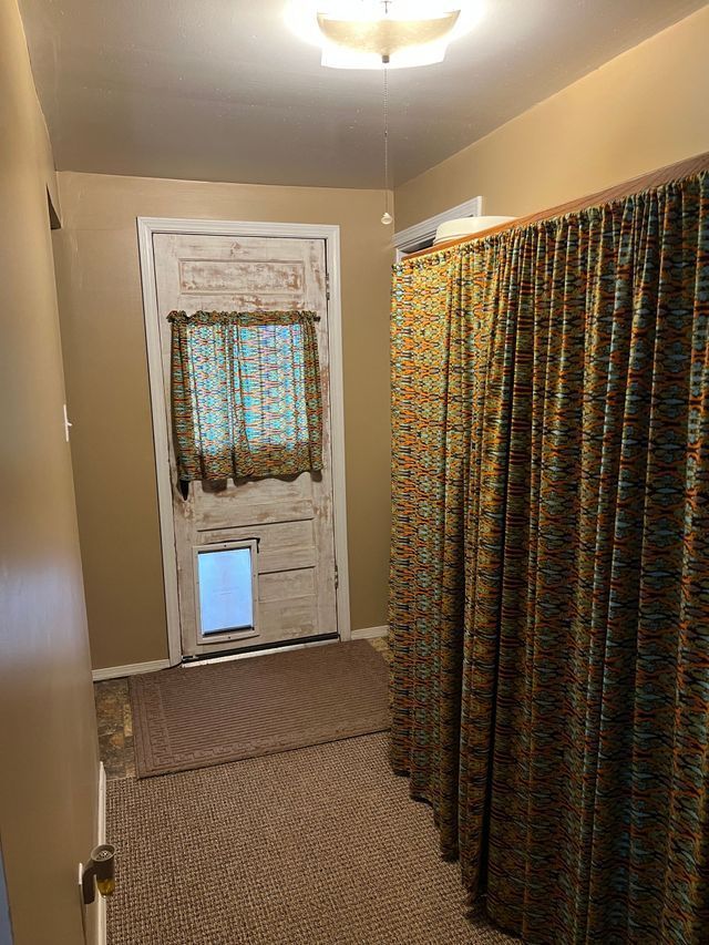A hallway with a door and curtains in a house.