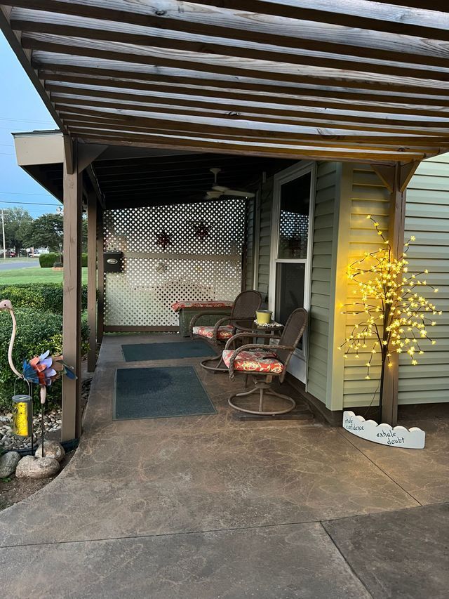 A patio with a pergola and chairs underneath it.
