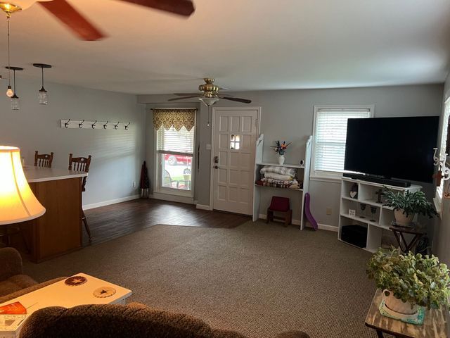 A living room with a ceiling fan and a flat screen tv.