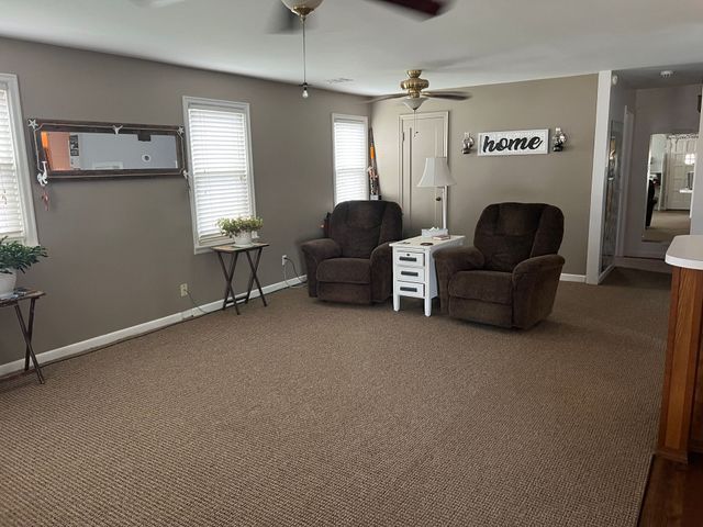 A living room with two chairs and a ceiling fan.