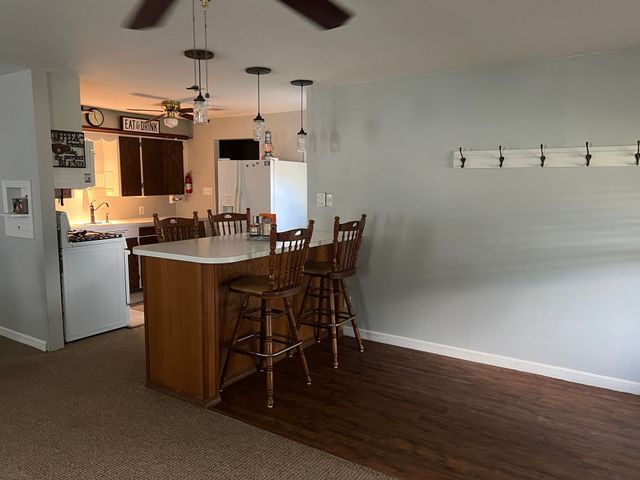 A kitchen with a bar and chairs and a ceiling fan.