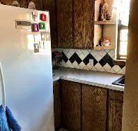A kitchen with wooden cabinets , a refrigerator , a sink , and a window.